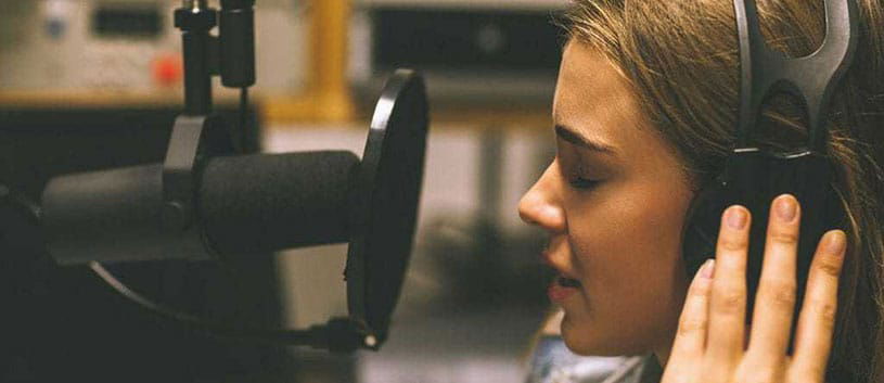 Young woman speaks into microphone at a radio broadcasting studio